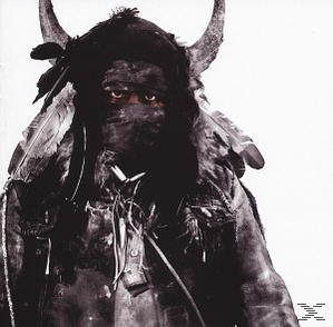 Person in Stammeskleidung mit Hörnern und Federn. Dunkle Gesichtsbemalung und eine schwarze Stoffmaske.