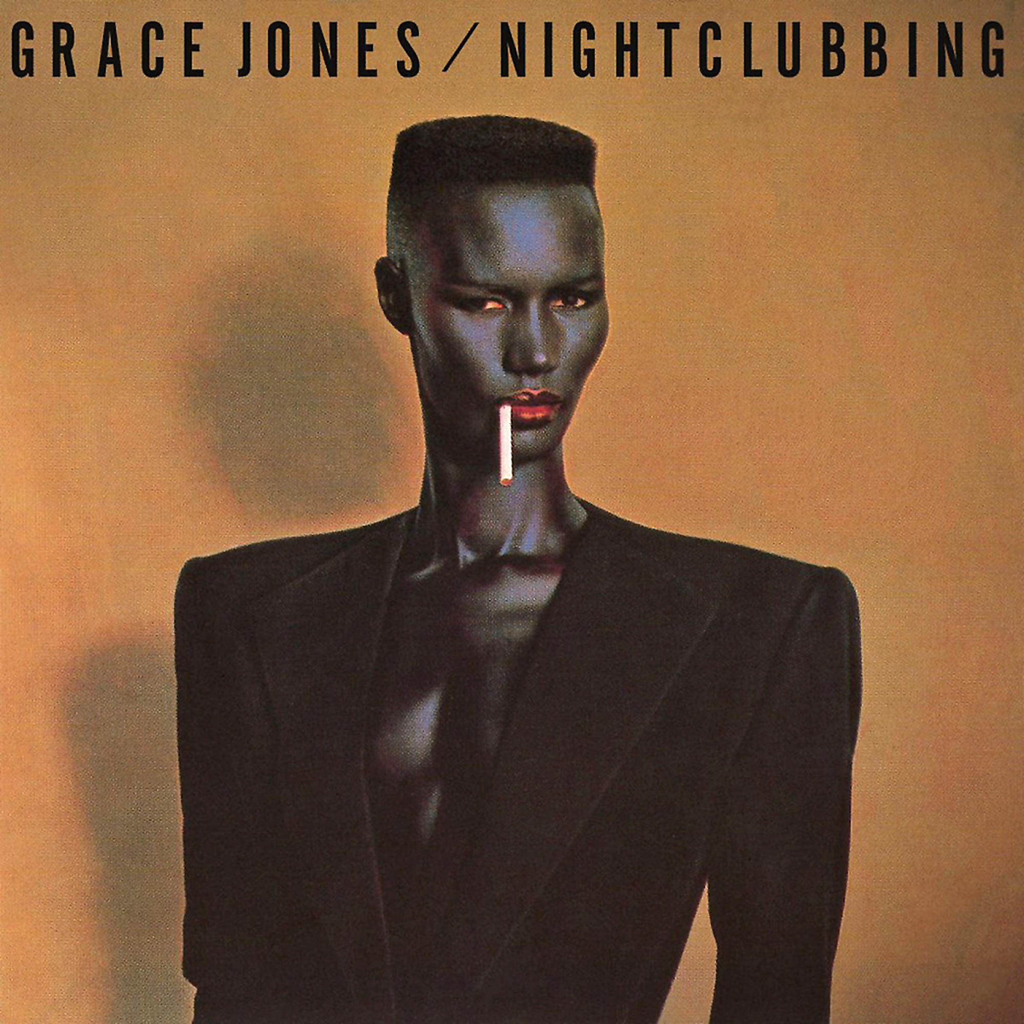 Eine Frau mit dunkler Haut, einer Zigarette im Mund, trägt eine schwarze Jacke. Der Text lautet 'GRACE JONES/NIGHTCLUBBING'.