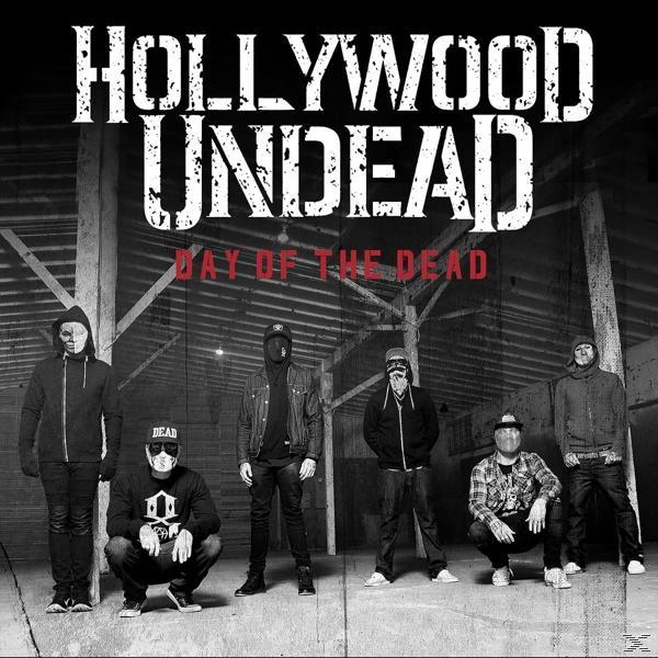 Bandmitglieder mit Masken stehen vor einer metallischen Struktur. Der Text lautet 'Hollywood Undead Day of the Dead'.