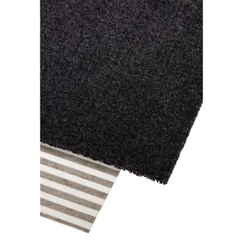 Black carpet on top of a striped rug. The carpet has a small piece of fabric.