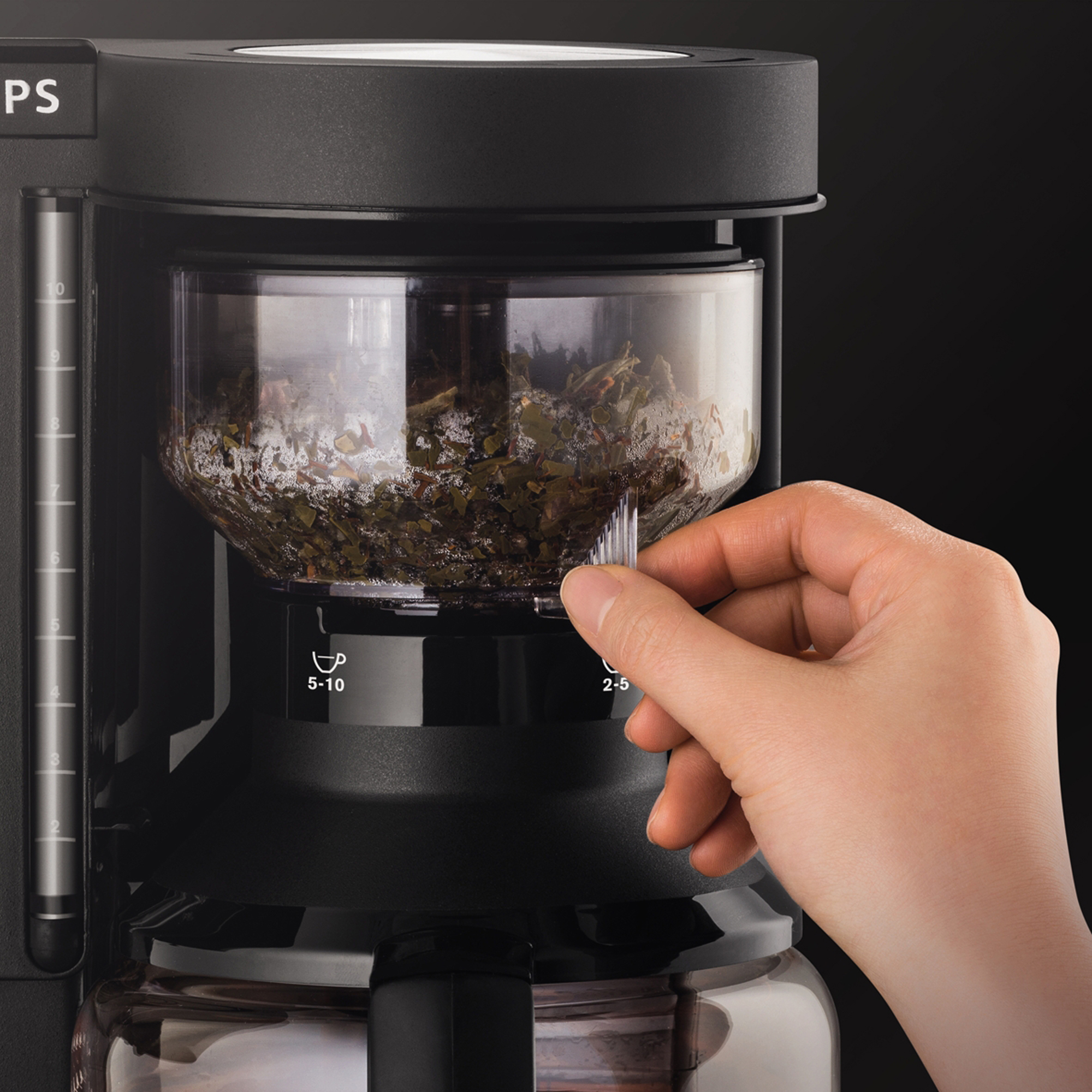 Die Hand einer Person, die den Filter an einer schwarzen Kaffeemaschine einstellt.