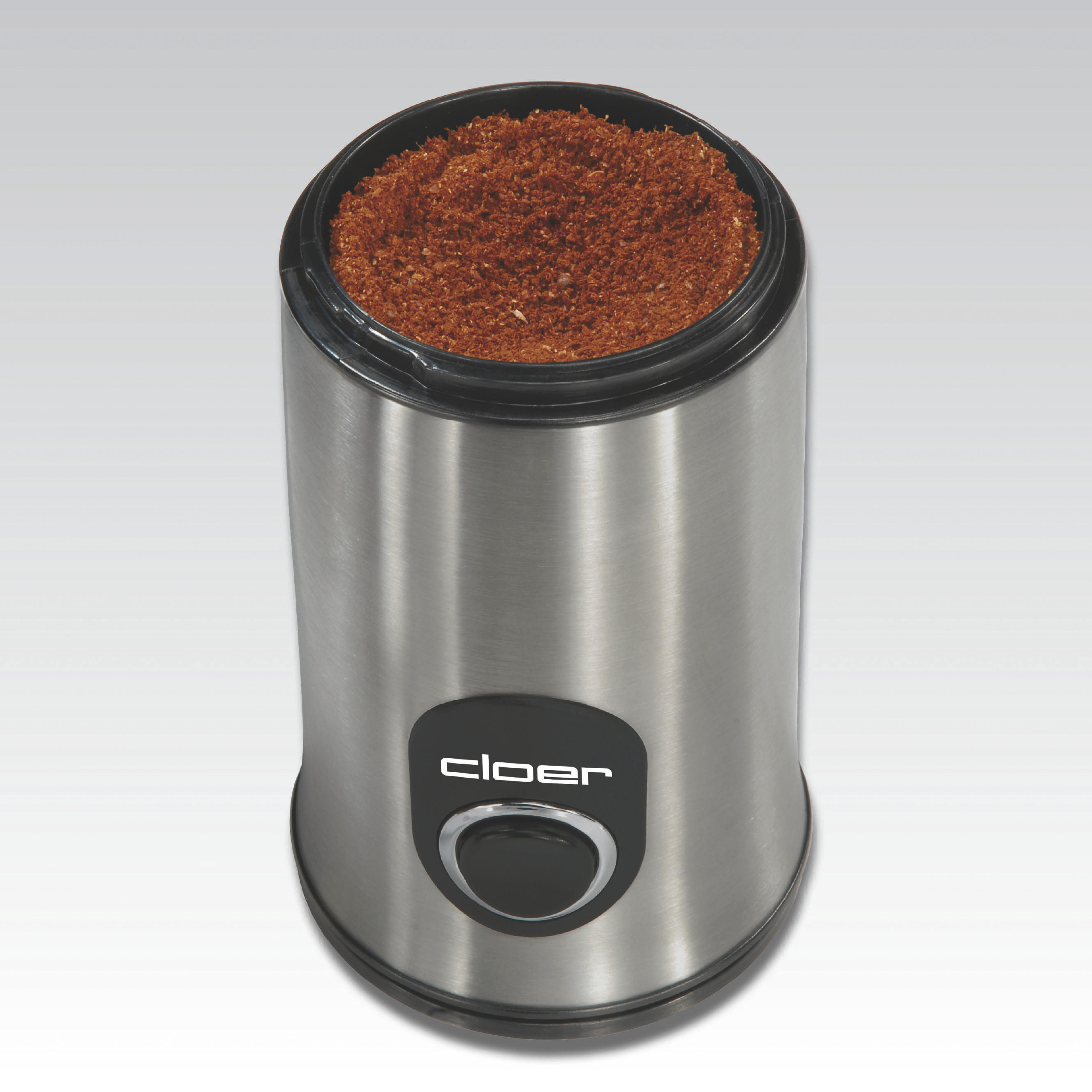 Eine kleine, silberne Kaffeemühle mit schwarzem Deckel. Gefüllt mit gemahlenem Kaffee.