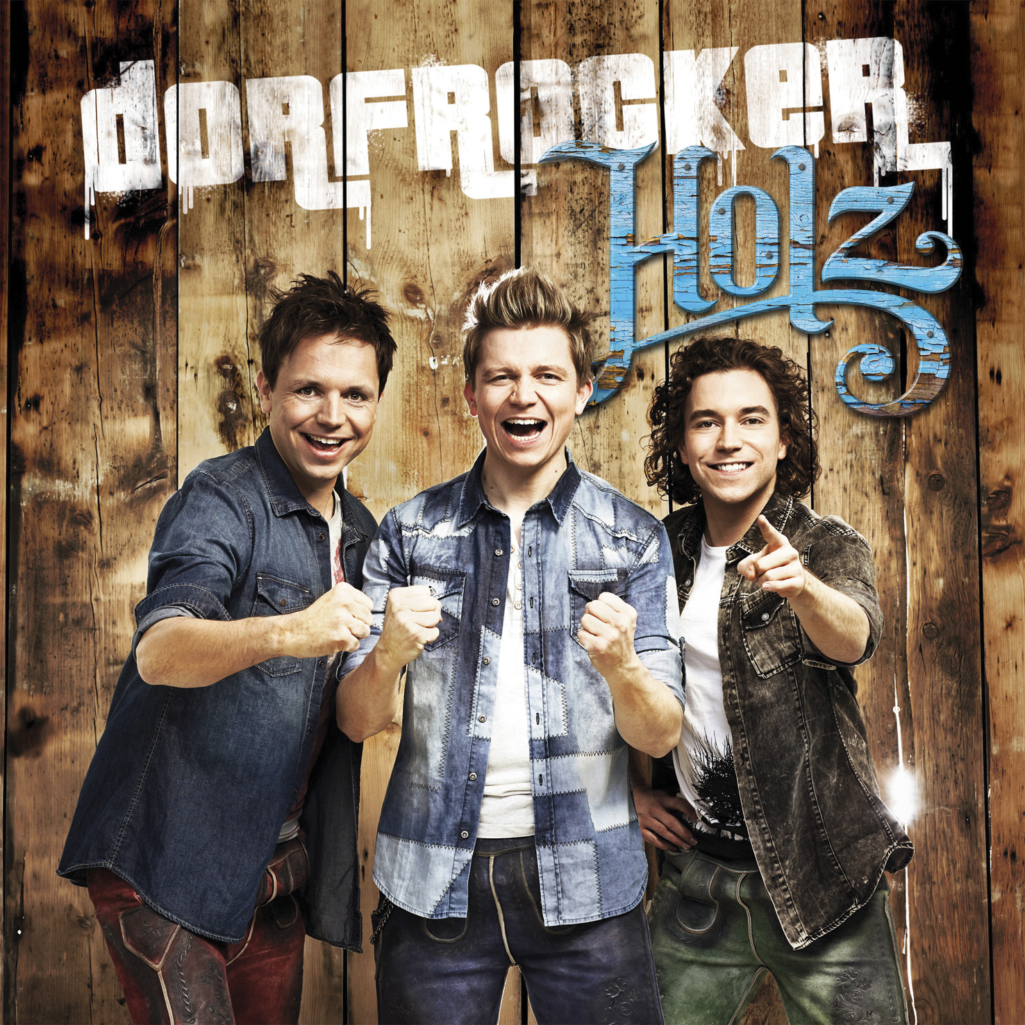 Dorfrocker Band, drei lächelnde Männer, Holzgrund.