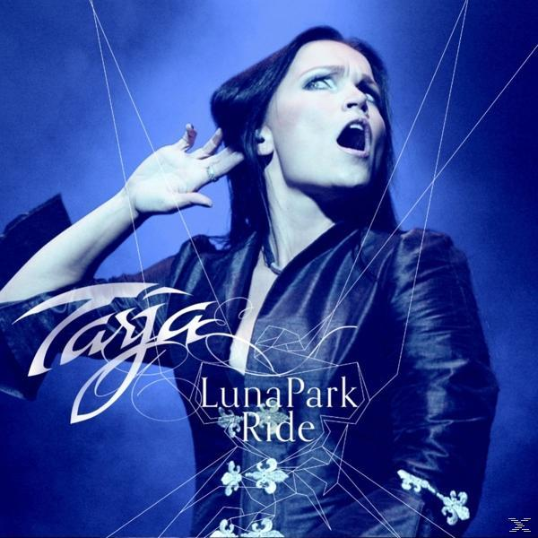 Frau auf der Bühne mit offenem Mund, Arm am Ohr und dem Namen 'Tarja' und dem Albumtitel 'LunaPark Ride'.