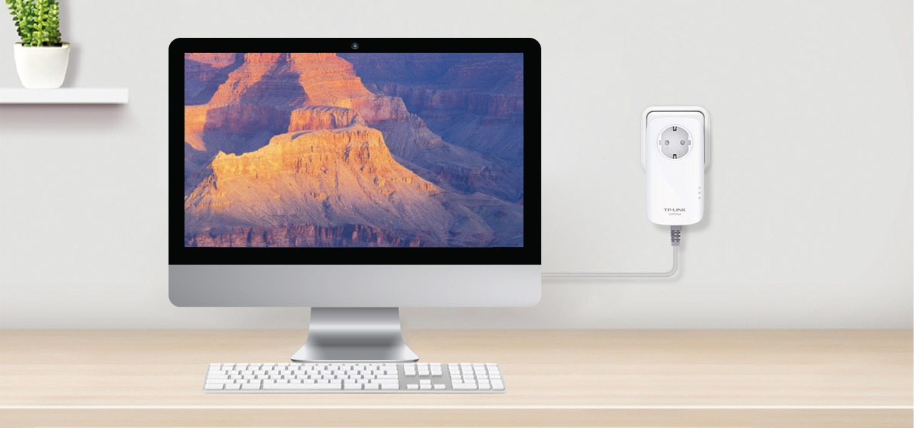 Computerbildschirm mit Canyon-Ansicht, mit weißem Steckdosenadapter an der Wand.