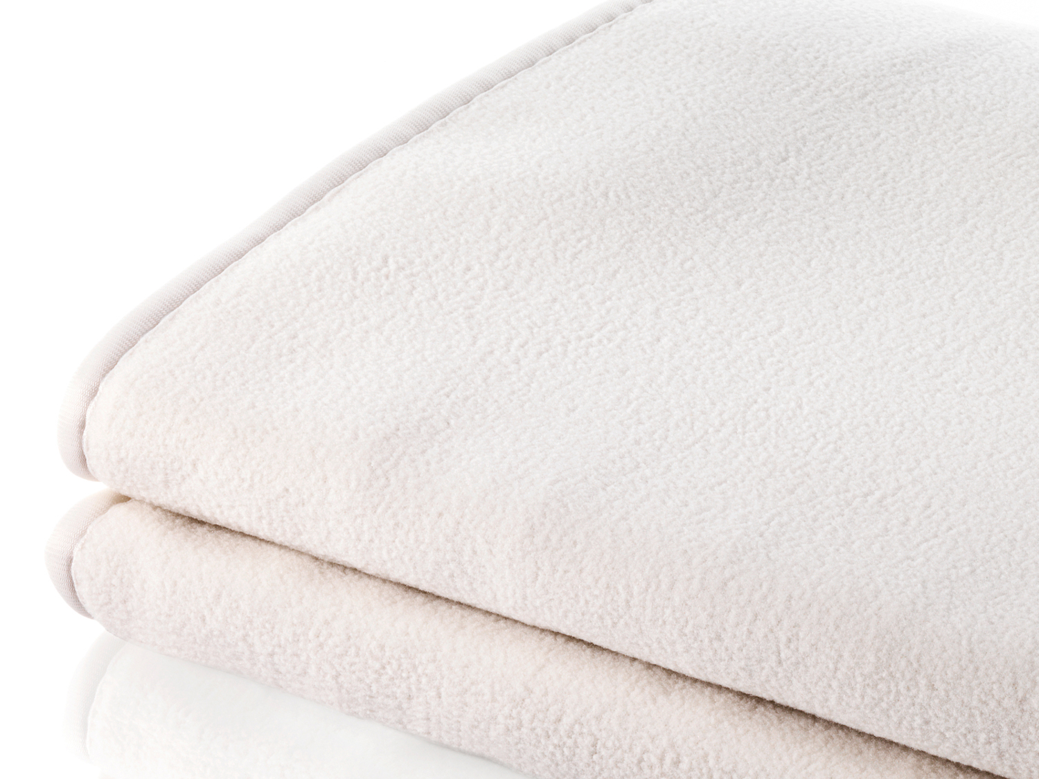 Coperta piegata, di colore chiaro, primo piano, su sfondo bianco.
