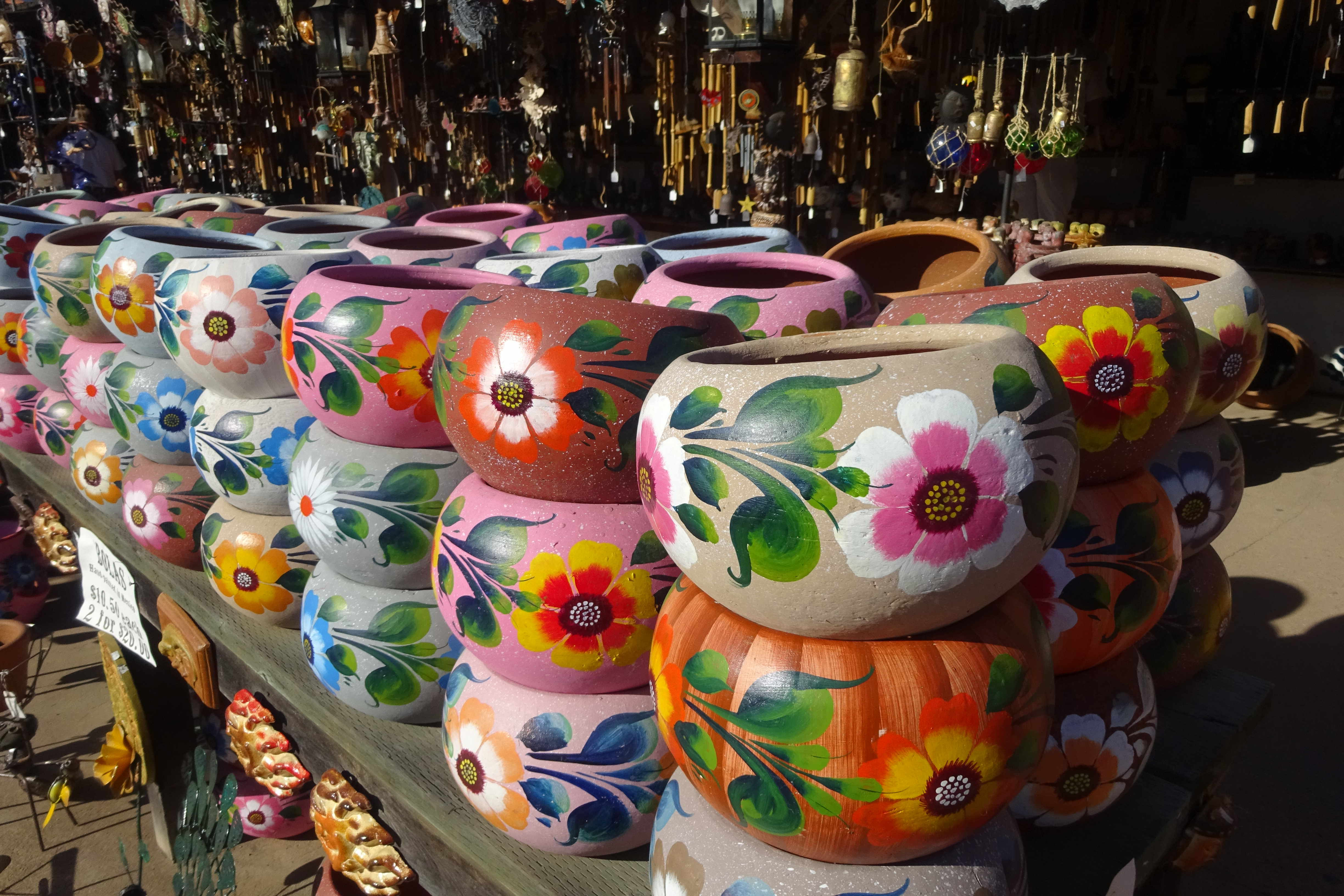 Bunte Blumentöpfe auf einem Holztisch gestapelt. Vielfalt an Farben und Blumendesigns.