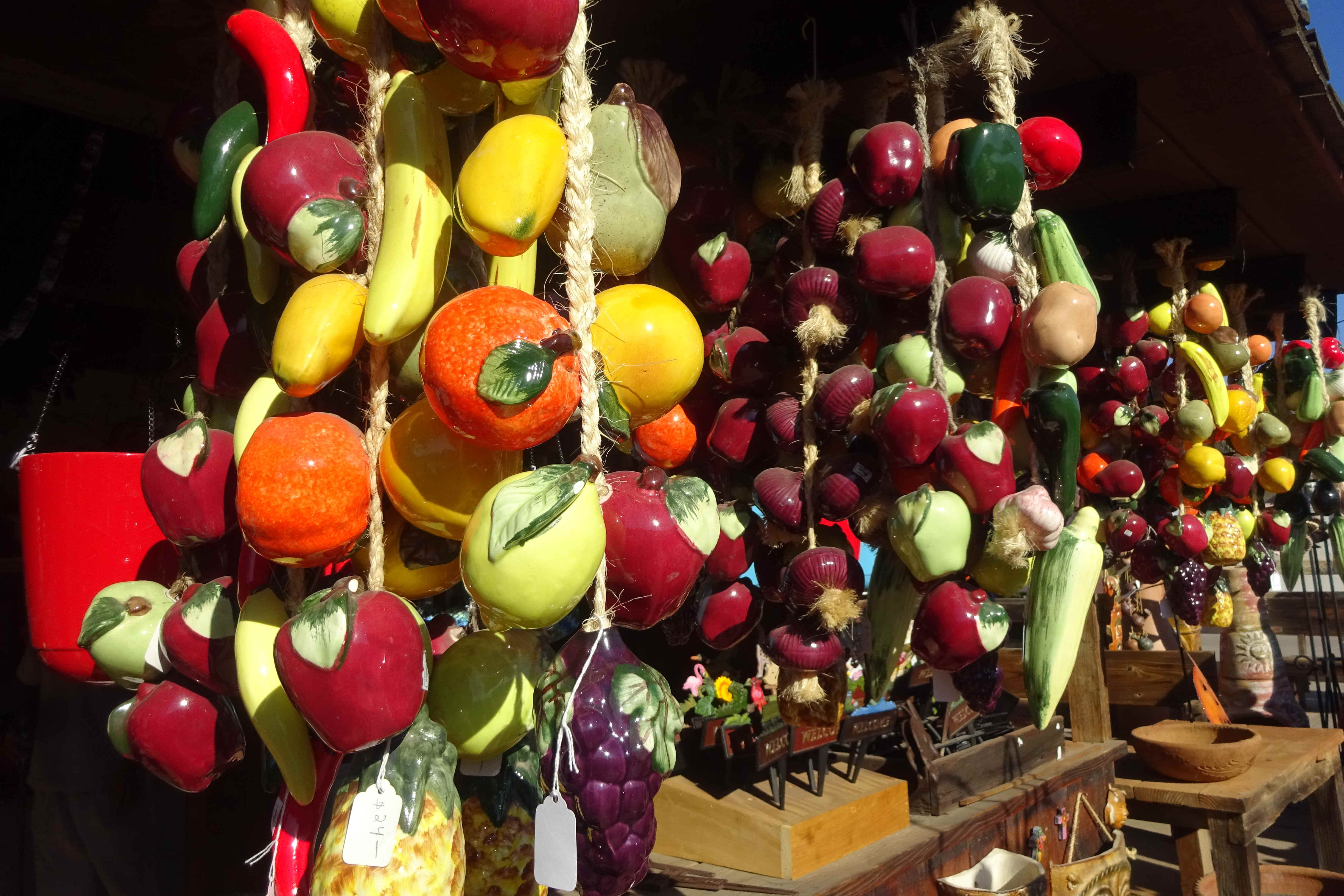 Hängende Ausstellung dekorativer Keramikfrüchte und -gemüse, verschiedene Farben und Formen.