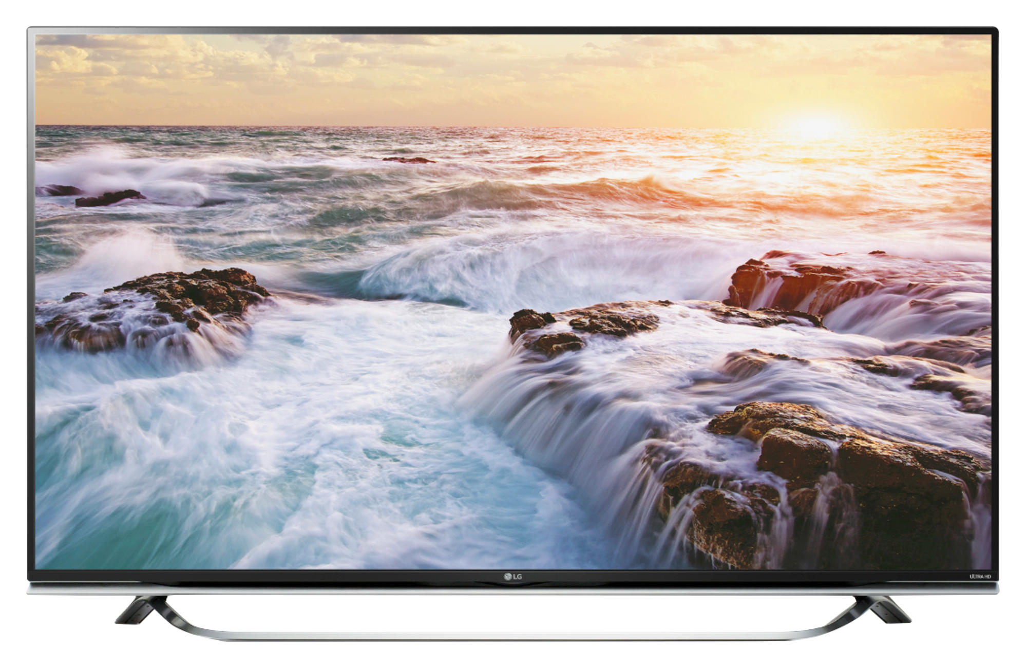 Pantalla de TV mostrando olas y atardecer. Rocas en primer plano, cielo al fondo.