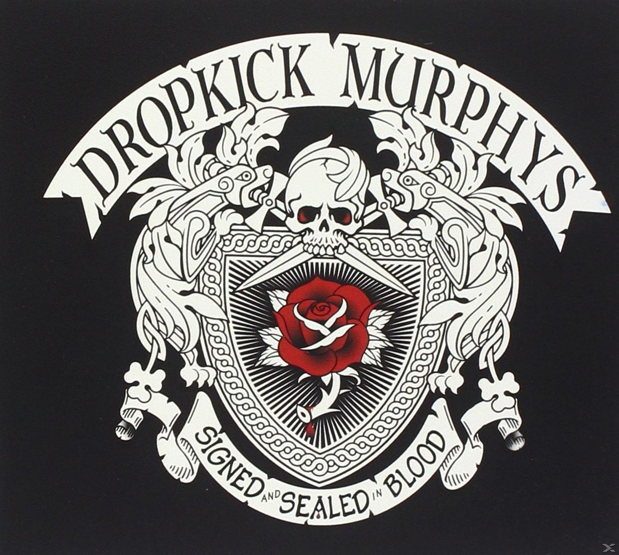 Albumcover, Dropkick Murphys Logo: ein Totenkopf mit einer Rose, umgeben von Schilden und Bannern. Schwarzer Hintergrund.