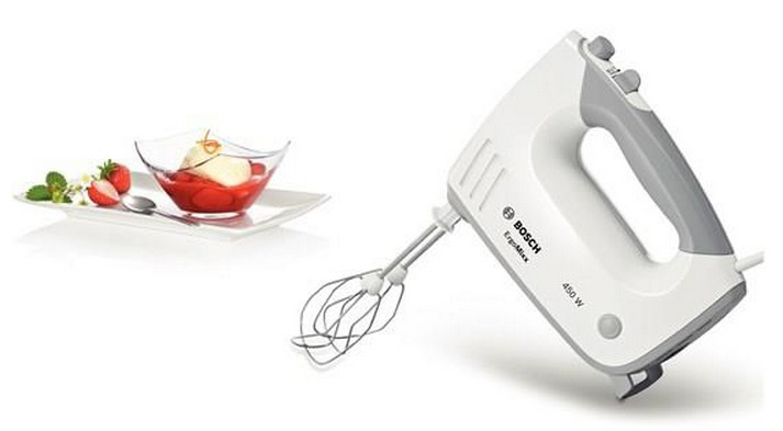 Mixeur à main à côté d'un dessert. Fond blanc.