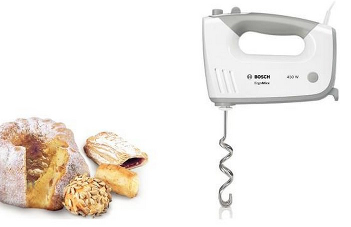 Un batteur à main blanc et des produits de boulangerie: un gâteau, une pâtisserie et un petit pain aux graines.