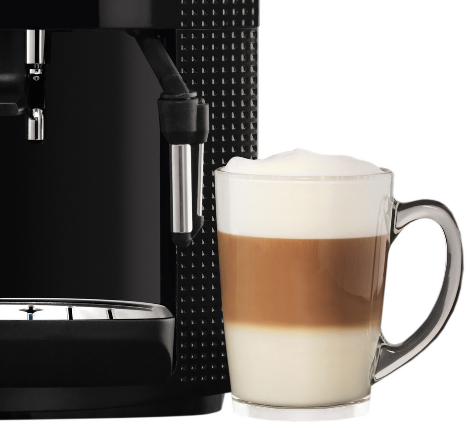 Een zwarte espressomachine naast een glas latte. De latte heeft lagen melk, espresso en schuim.