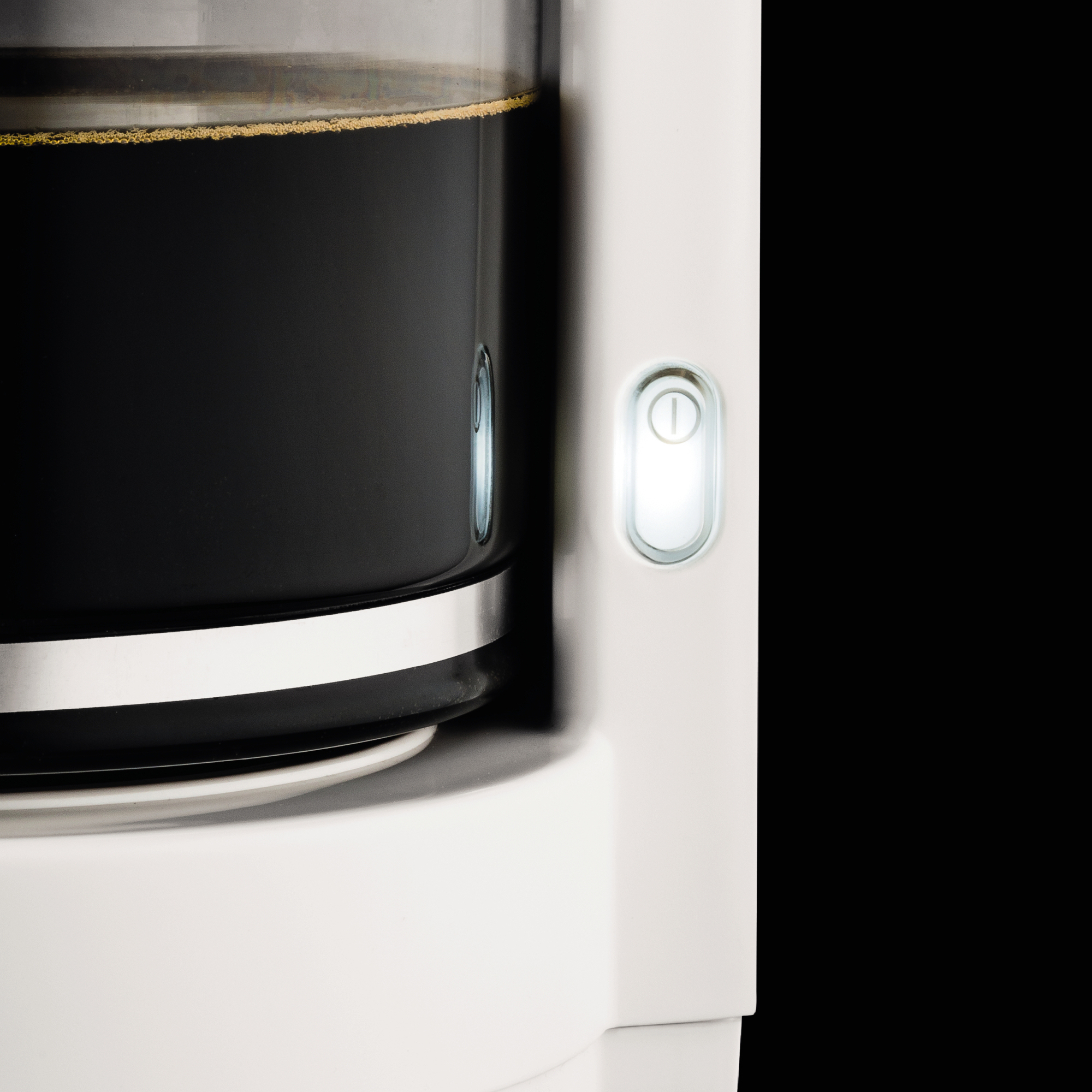 Kaffeemaschine: Nahaufnahme von Kaffee und beleuchtetem Einschaltknopf.