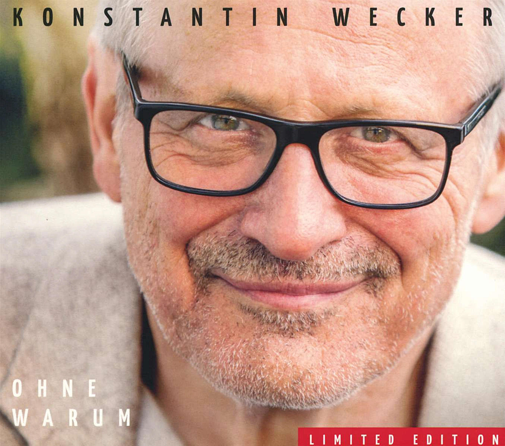 Nahaufnahme eines älteren Mannes mit Brille und Schnurrbart, Text oben: 'Konstantin Wecker'.