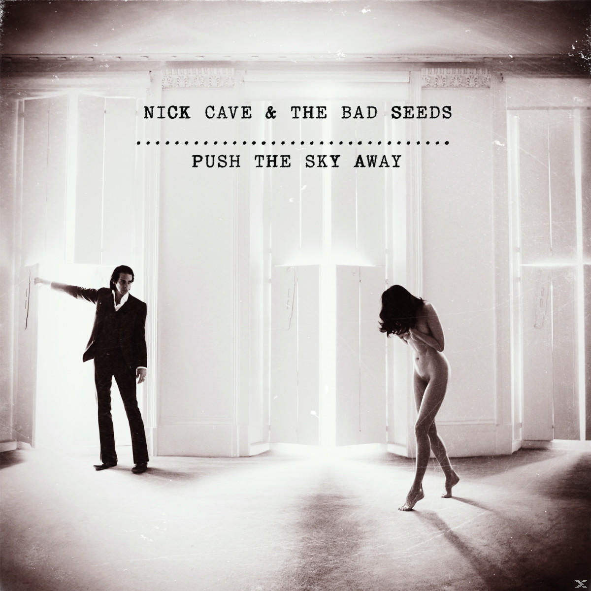 Bild von Nick Cave und einer nackten Frau in einem Raum mit hellem Licht und dem Text 'Push the Sky Away'.