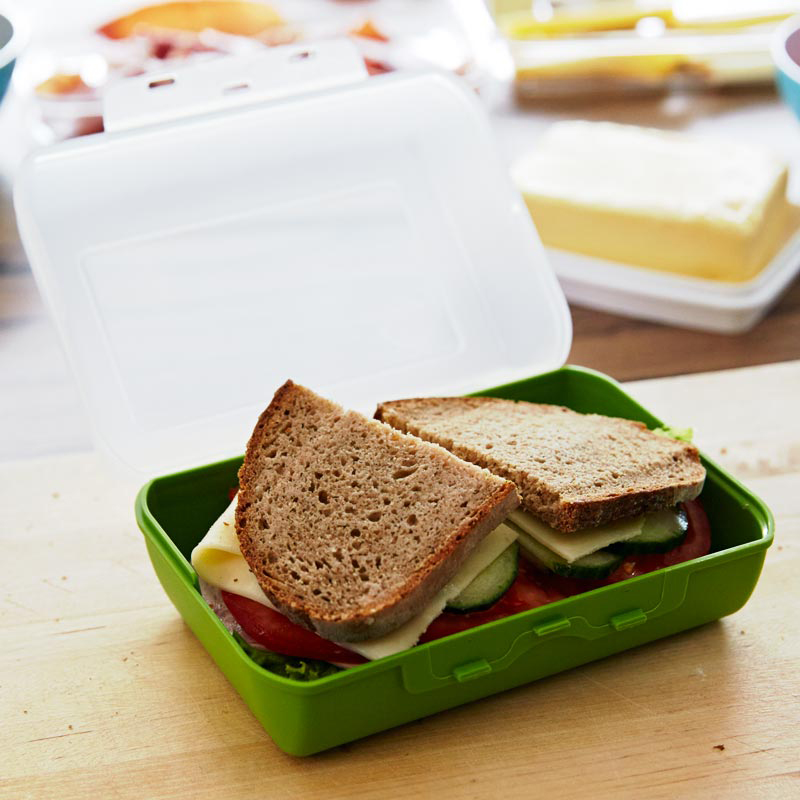 Grüne Brotdose mit Sandwich, Tomate, Käse und Salat.