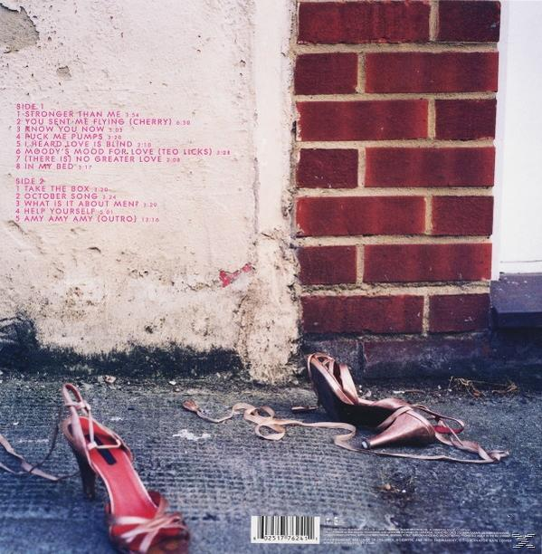 High Heels und Bänder auf Beton in der Nähe einer Backsteinmauer. Text listet Songs auf dem Album.