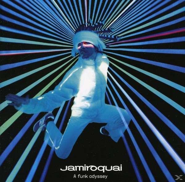 Jamiroquai Albumcover. Ein Mann im weißen Anzug mit farbenfrohem Hintergrund.