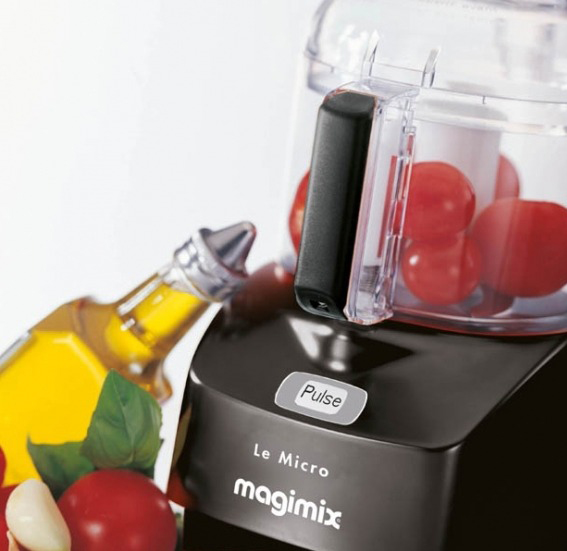 Een keukenmachine met tomaten en olie. Het label luidt Le Micro Magimix met een pulse-knop.