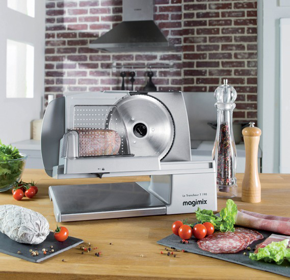 Vlees snijmachine op een houten tafel, met etenswaren.