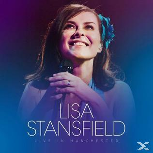 Lisa Stansfield, lächelnd, singt ins Mikrofon. Blauer und violetter Hintergrund.