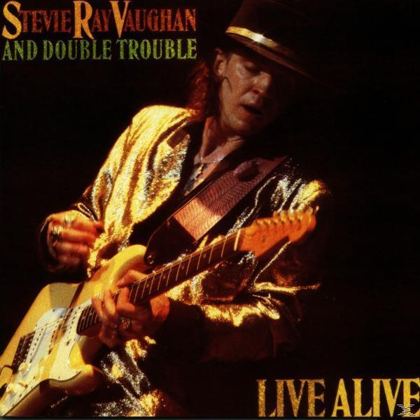 Stevie Ray Vaughan spielt Gitarre auf der Bühne. Das Albumcover trägt die Aufschrift "Live Alive" und zeigt den Namen der Band.