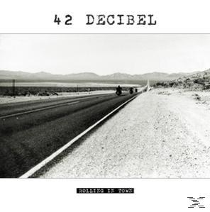 Schwarz-Weiß-Foto einer Straße mit Motorrädern, Text oben '42 DECIBEL', unten 'Rolling In Town'.