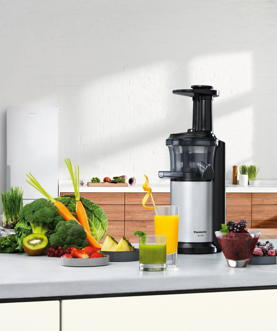 Eine moderne Küchenszene mit einem Entsafter, Gemüse und Saftgläsern. Gesunde Ernährung.