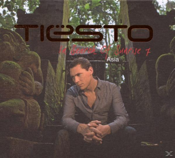 Album borító: Tiësto, In Search of Sunrise 7. Tiësto lépcsőn ül kőépítmények és dzsungel háttér előtt.