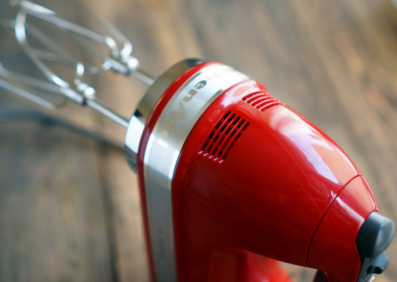 Close-up van een rode KitchenAid handmixer. Het bovenste gedeelte met de merknaam is scherp.
