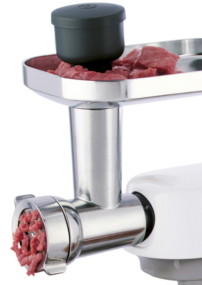 Meat grinder with raw meat in the tray and ground meat coming out. White background.