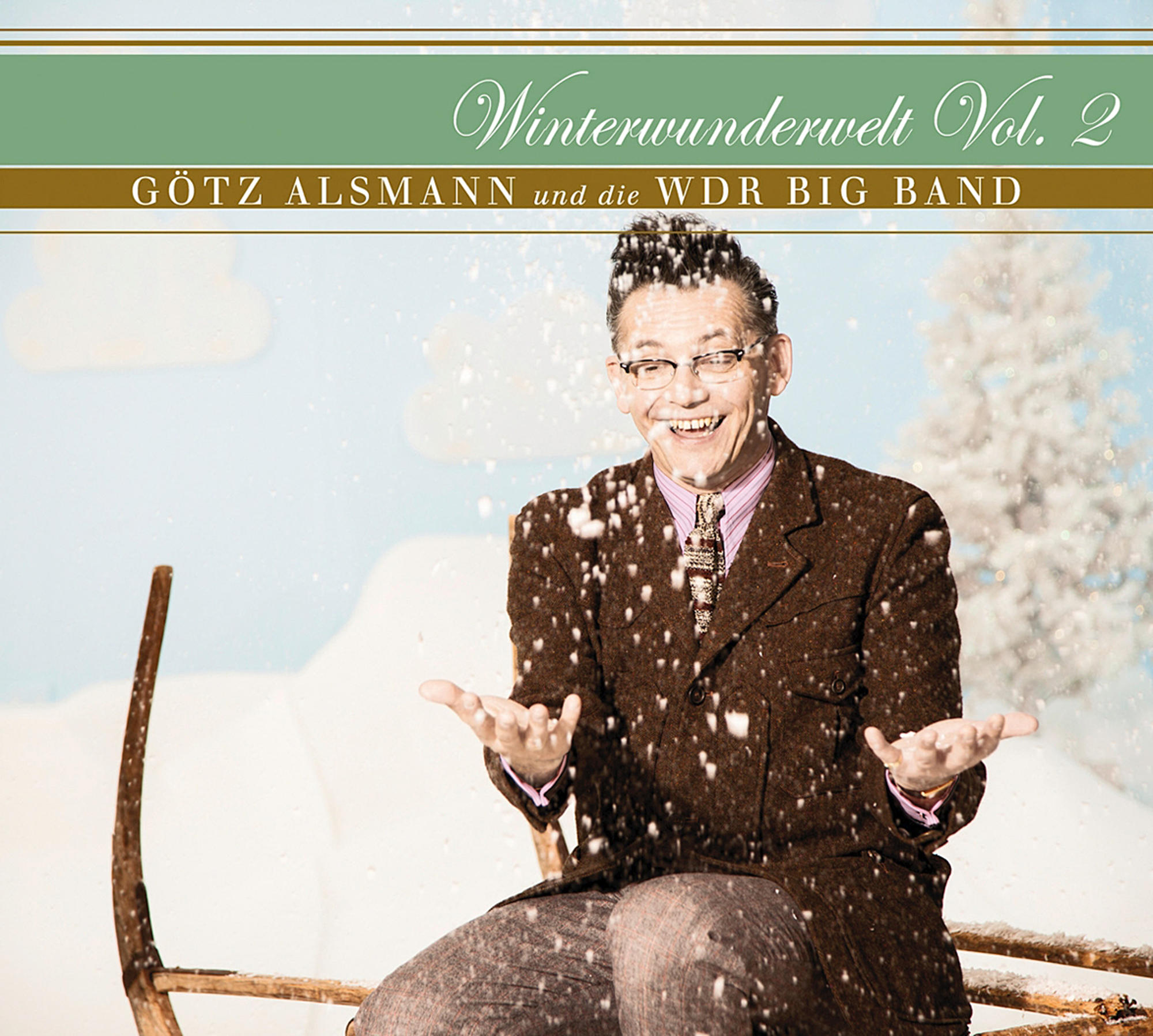 Mann in braunem Anzug lacht und wirft Schnee, trägt Brille. Titel: Winterwunderwelt Vol. 2. Hintergrund: Schnee, Winterszene.