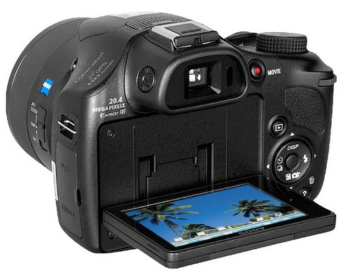 Digitalkamera, Sony, schwarz, mit einem Bildschirm, der eine Strandszene zeigt, geöffnet, um den Bildschirm zu zeigen.