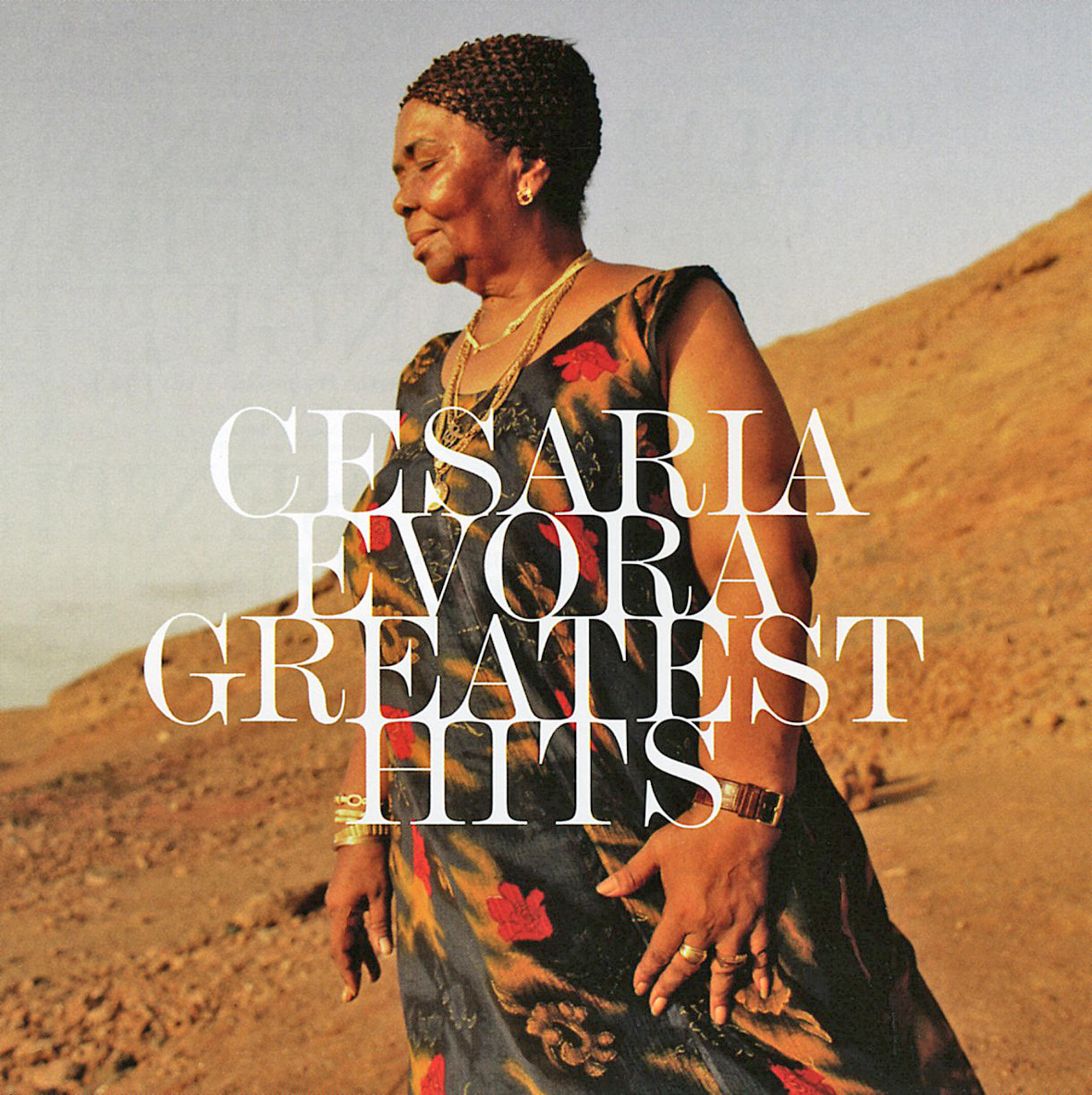 Albumcover von Cesária Évora. Sie trägt ein Blumenkleid und Schmuck und steht in einer Wüste. Der Albumtitel ist überlagert.