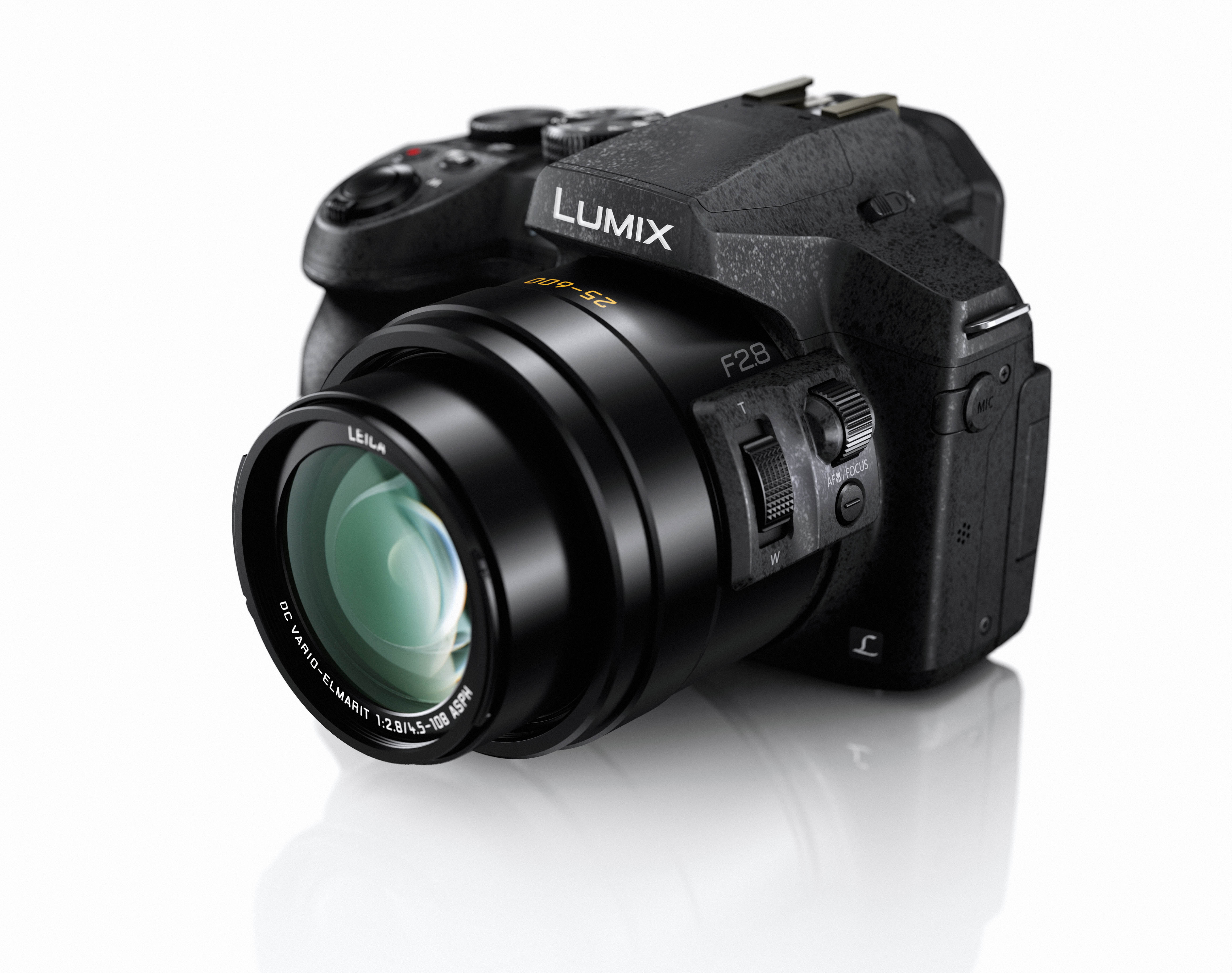 Fotocamera nera su sfondo bianco. Obiettivo e corpo visibili, contrassegnati 'Lumix'. Pulsanti e ghiere presenti.