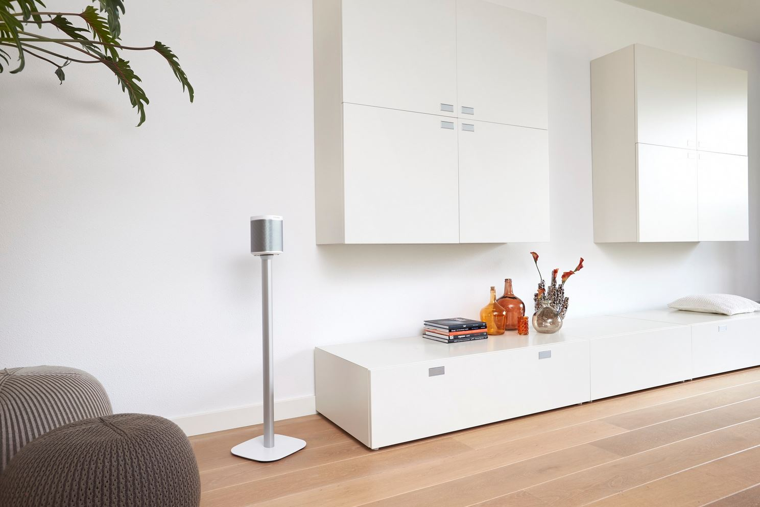 Salon moderne avec armoire blanche, haut-parleur, parquet et éléments décoratifs.