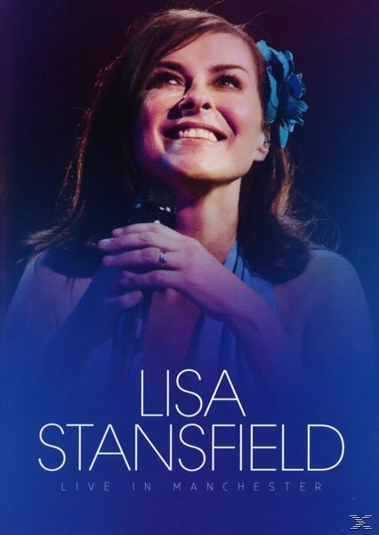 Lisa Stansfield auf der Bühne, singt in ein Mikrofon, mit einer blauen Blume im Haar.