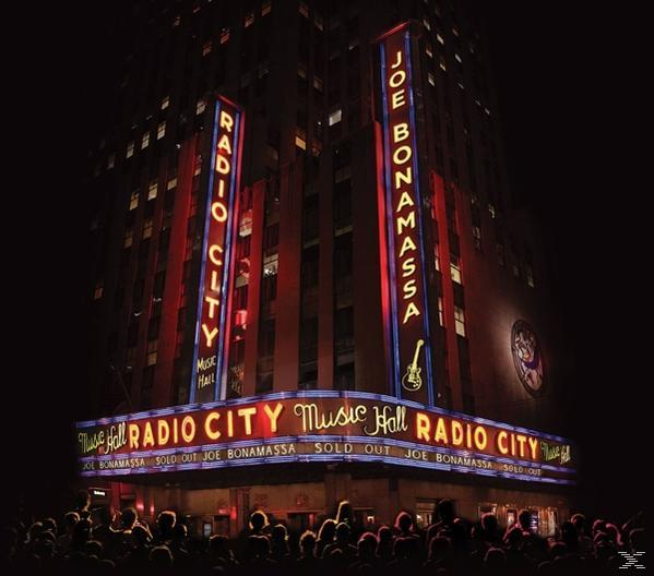 Nachtaufnahme der Radio City Music Hall mit Neonlichtern. Menschen im Vordergrund, ausverkauft.