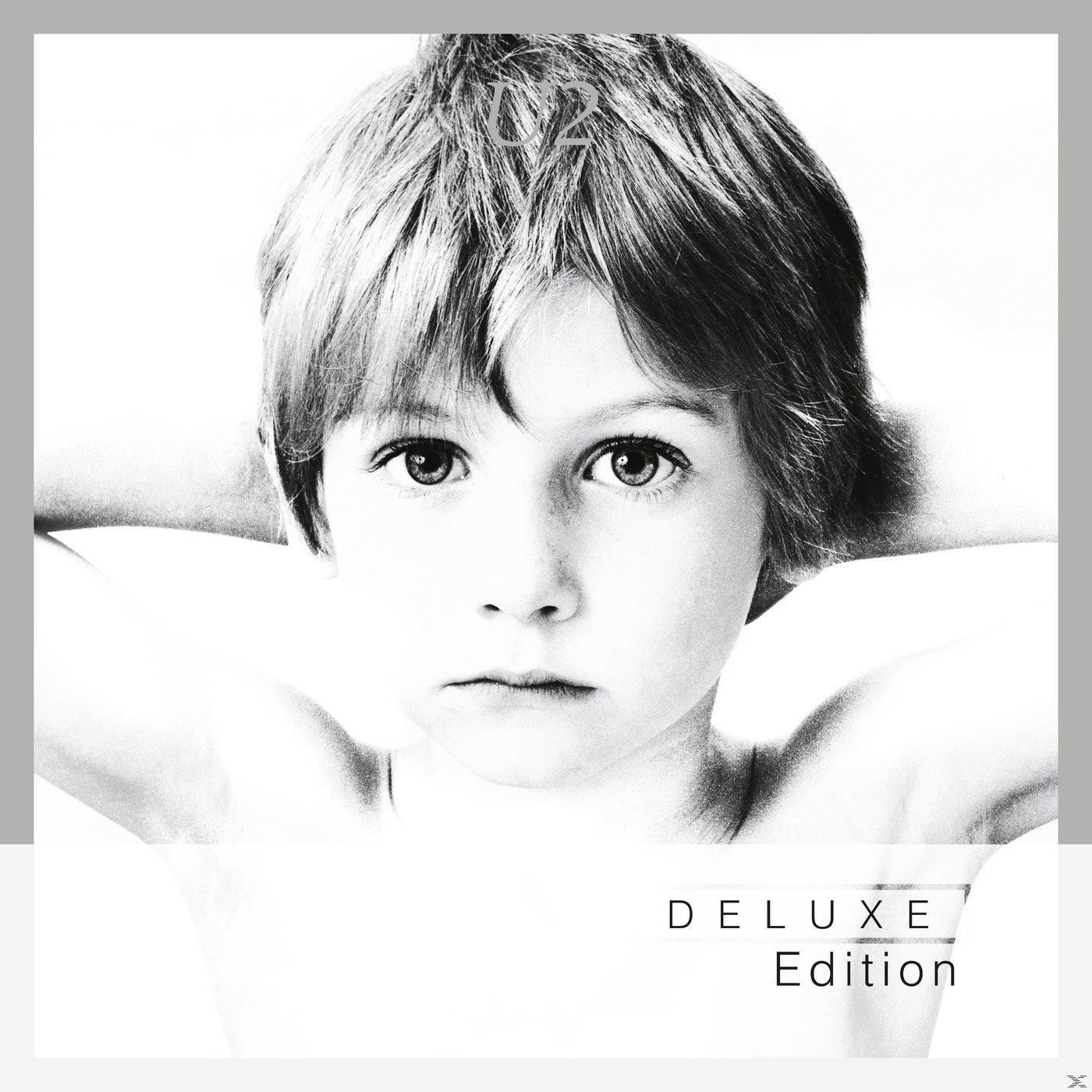Schwarz-Weiß-Foto eines jungen Jungen mit den Händen hinter dem Kopf; 'Deluxe Edition'.