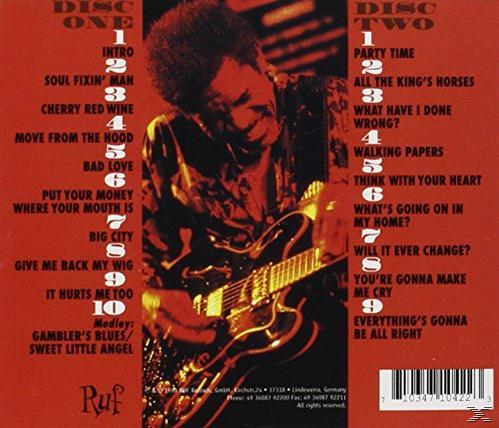 Album-Rückseite mit Titelliste und Bild eines Mannes, der Gitarre spielt, auf rotem Hintergrund.