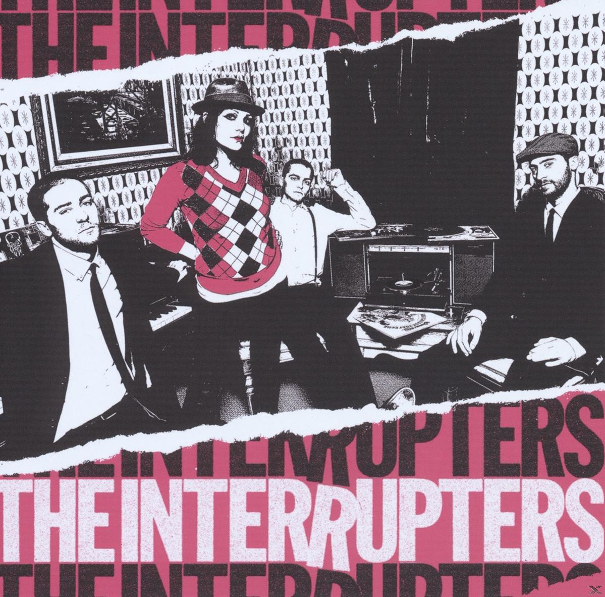 Albumcover mit Band in einem Raum. Text lautet "THE INTERRUPTERS" in Pink und Weiß.