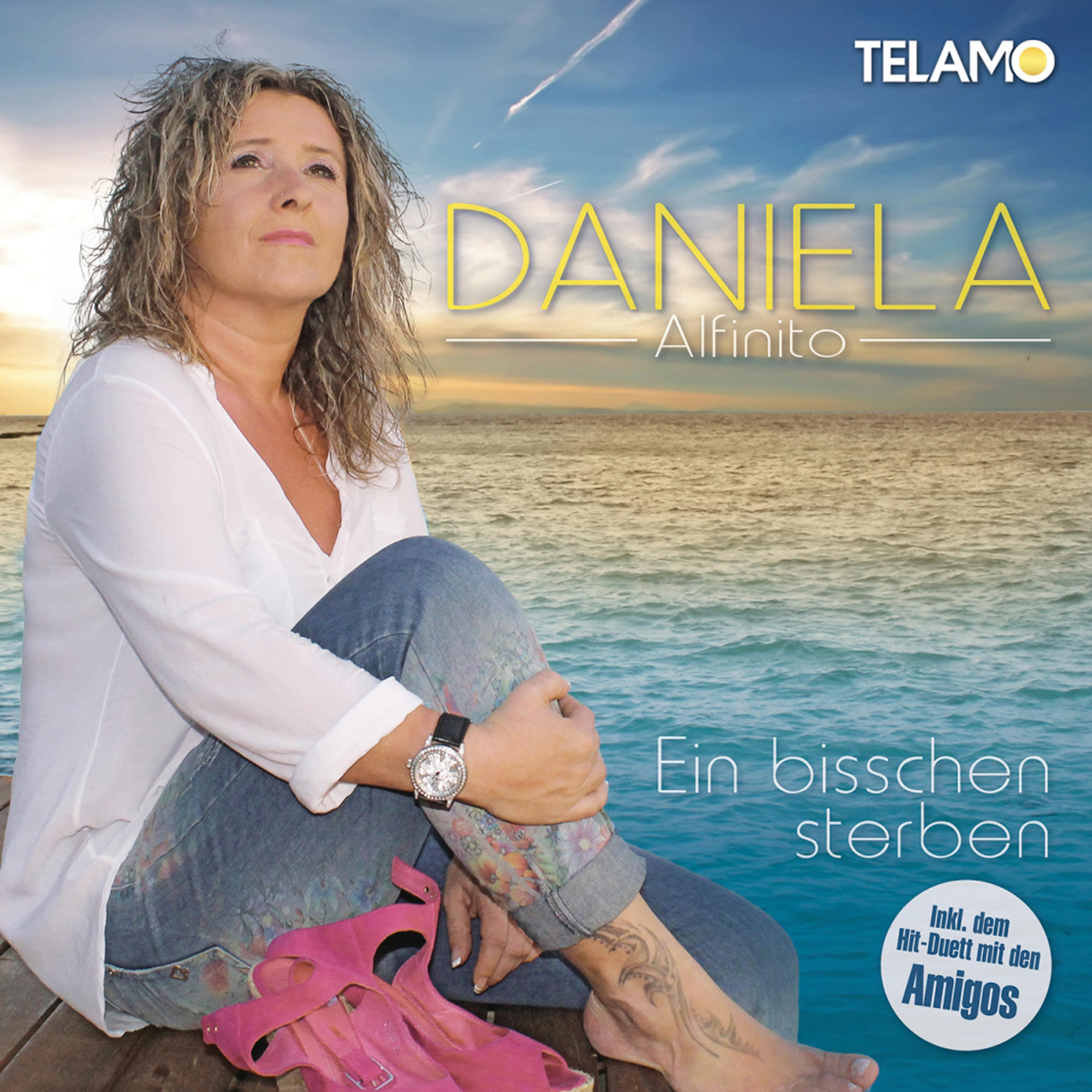Eine Frau sitzt am Meer, trägt ein weißes Oberteil, Jeans und rosa Schuhe. Das Albumcover ist sichtbar.