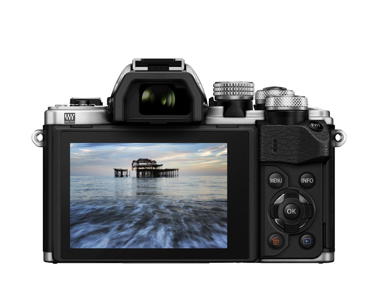 Eine silber-schwarze Digitalkamera zeigt auf dem Bildschirm eine Ozeanszene mit einem Pier. Knöpfe und Räder sind sichtbar.