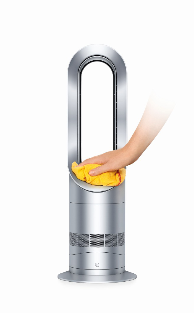 Die Hand einer Person reinigt einen silbernen Dyson-Ventilator mit einem gelben Tuch auf weißem Grund.
