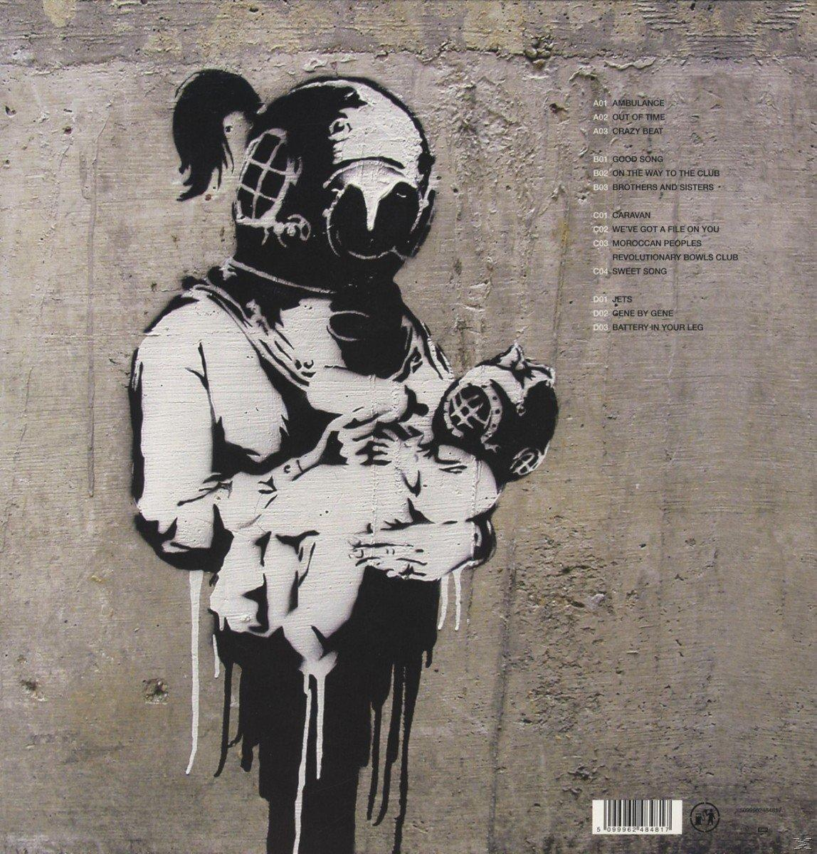 Egy búvár graffitije, aki egy babát tart egy szürke betonfalon.