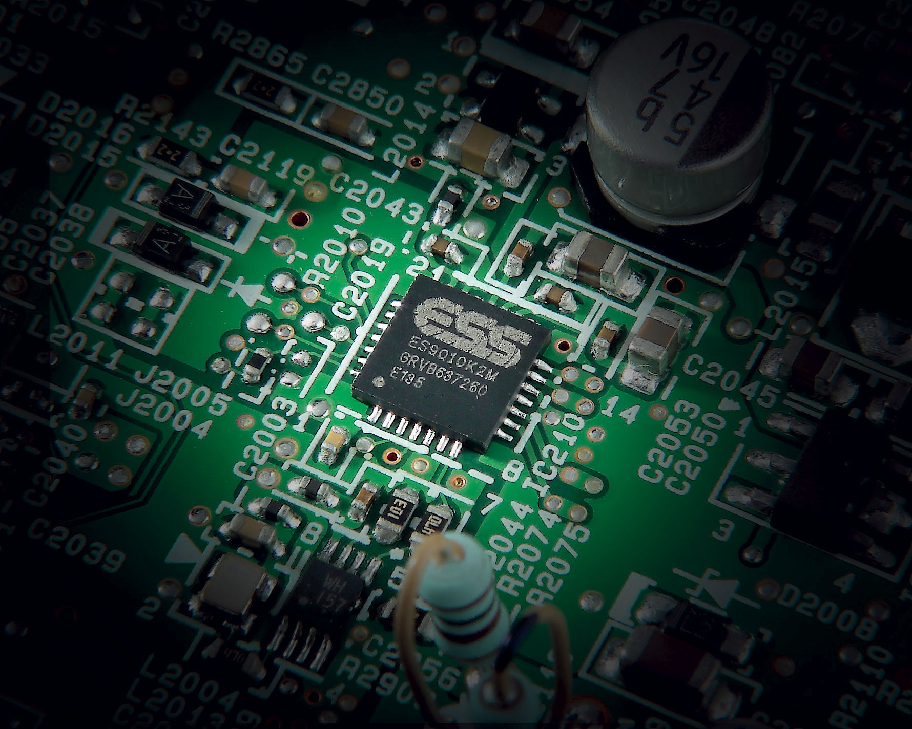 Nahaufnahme einer grünen Leiterplatte mit einem Chip mit der Aufschrift 'ESS' und Komponenten.