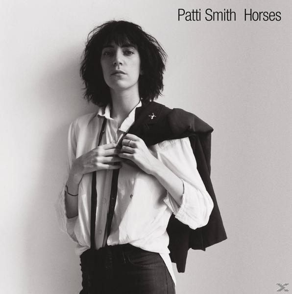 Schwarzweißfoto von Patti Smith in weißem Hemd und Jacke.