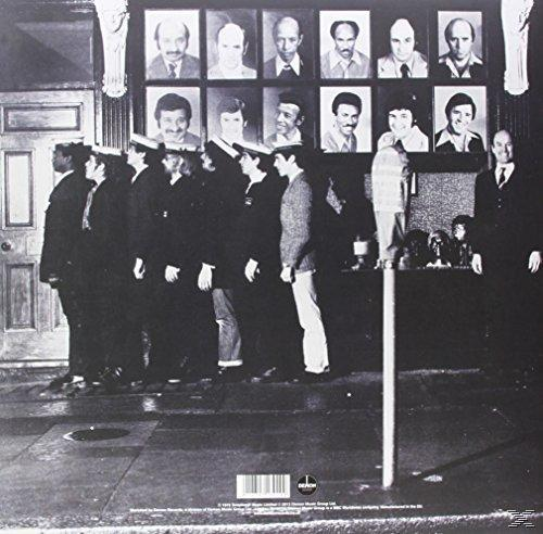 Schwarz-Weiß-Foto von Männern in Uniform, die in einer Reihe stehen, mit Porträts über ihnen.