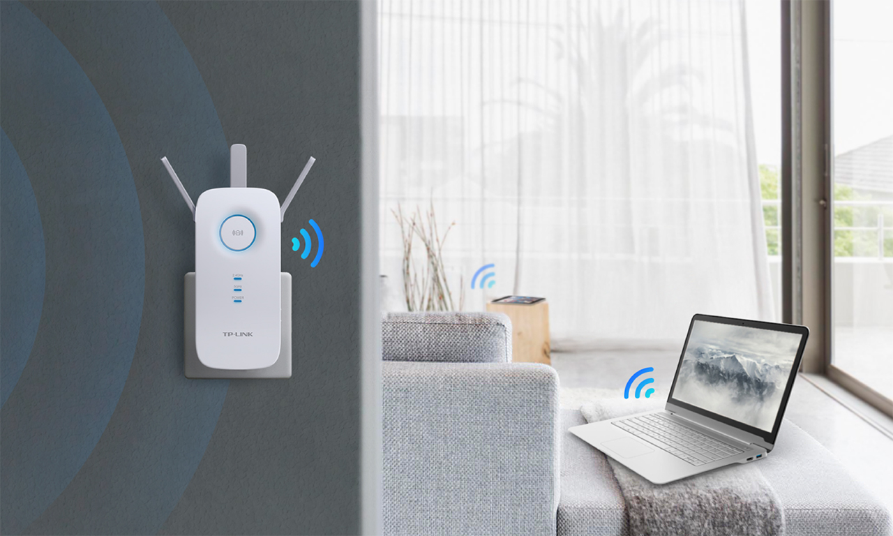 Een wifi-extender is aangesloten op een muur. Een laptop en een tafel staan op de achtergrond.